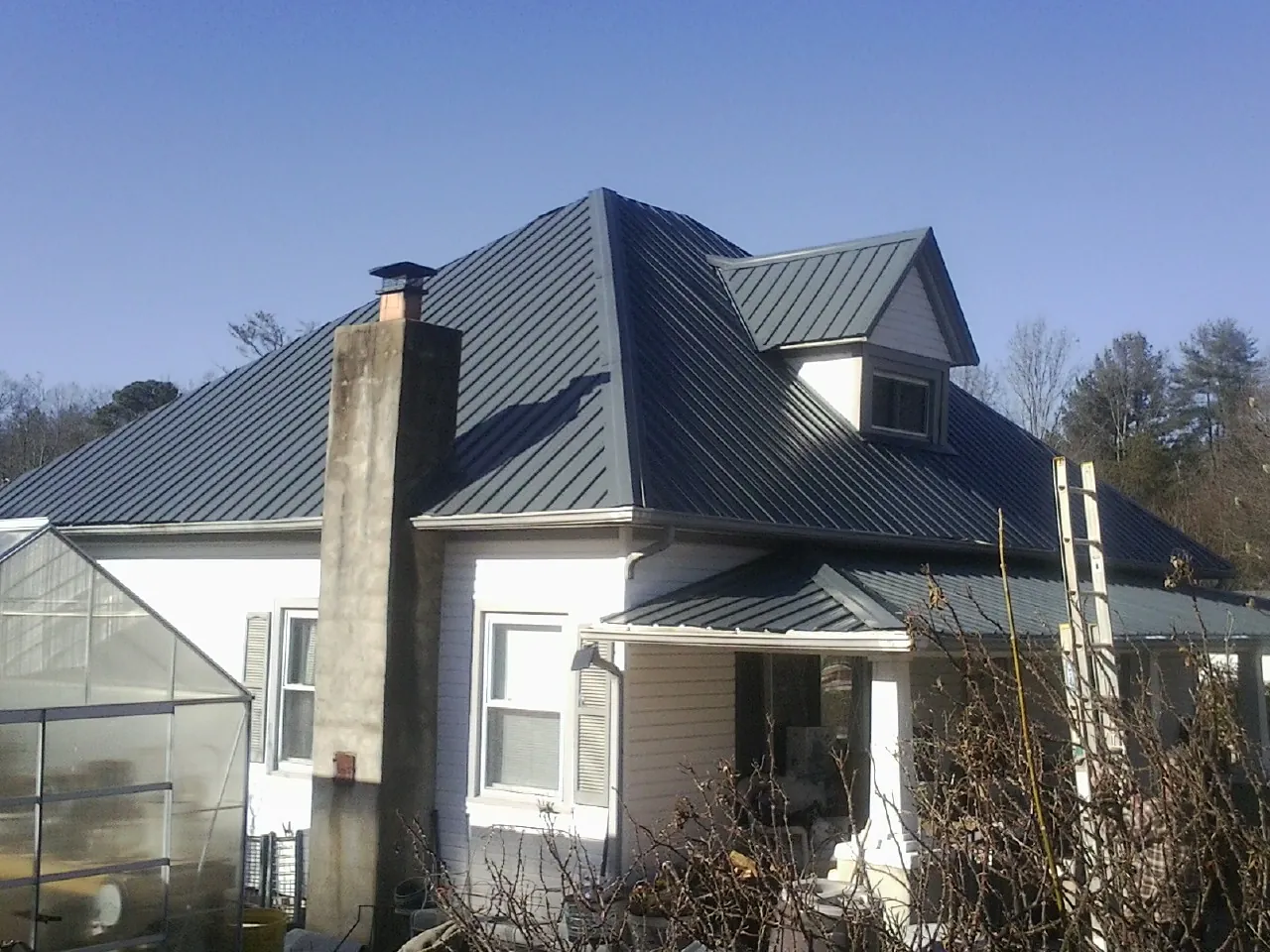 Dark blue standing seam metal roof on a white farmhouse with dormer — Slate & Tile Roof Repair by Roofing Brothers in Talbott