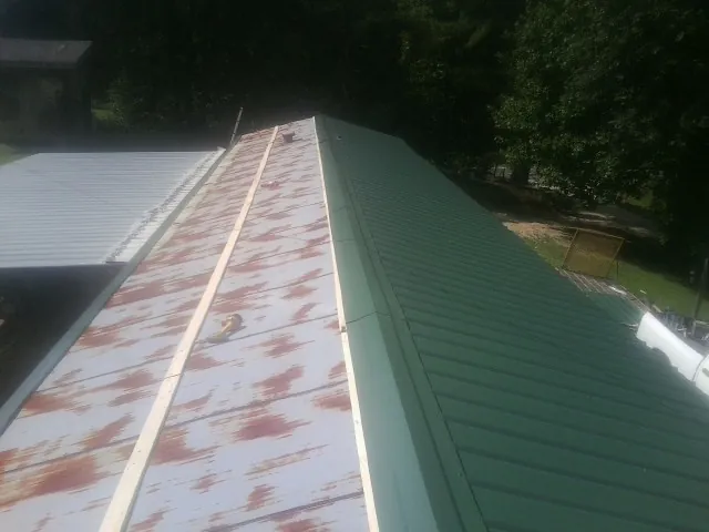 Old rusted panels beside newly installed green metal roofing — Wind Damage Roof Repair by Roofing Brothers in Talbott