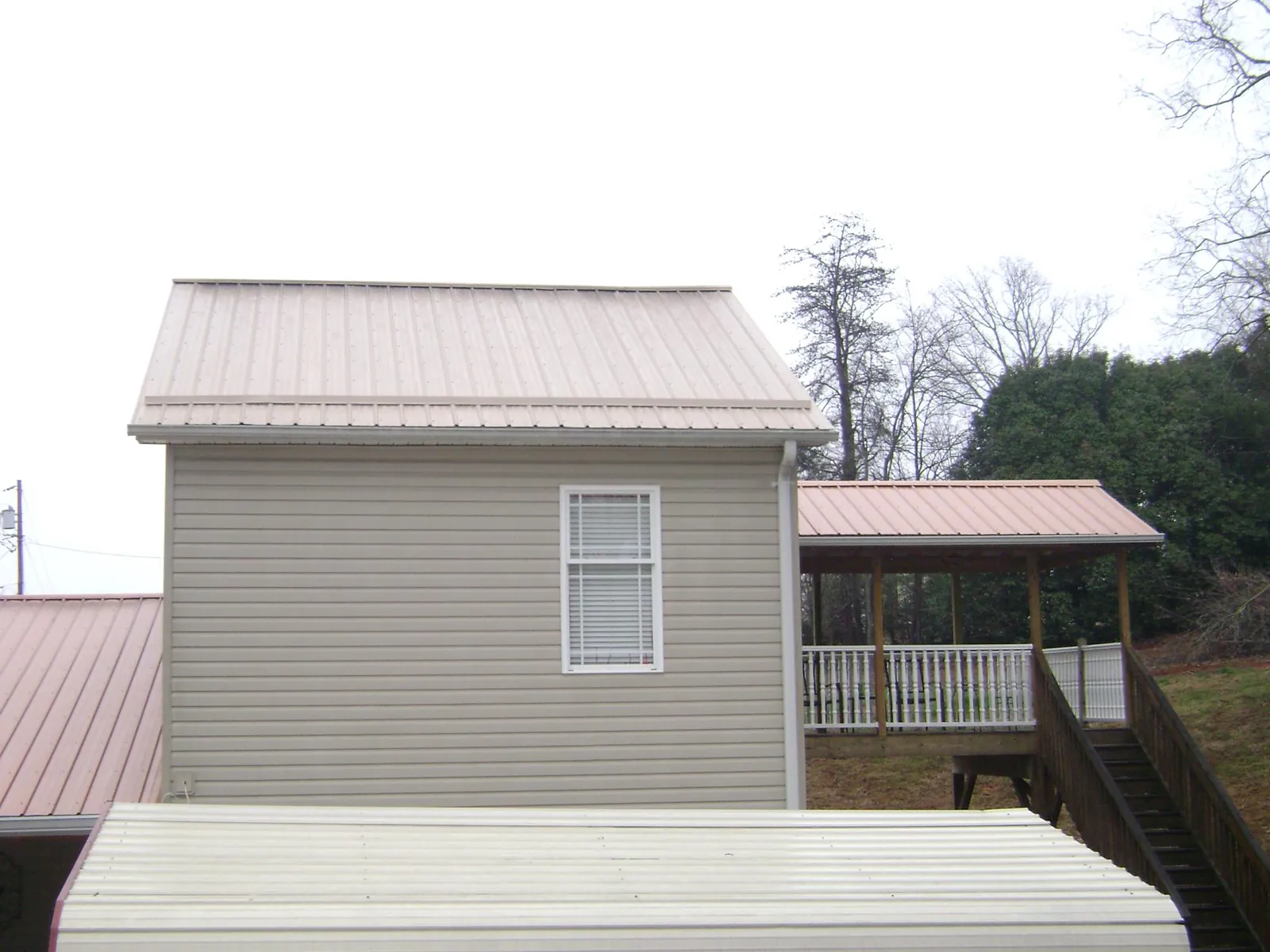Tan metal roofs on a two story addition and attached porch, from a Roof Replacement job in Talbott