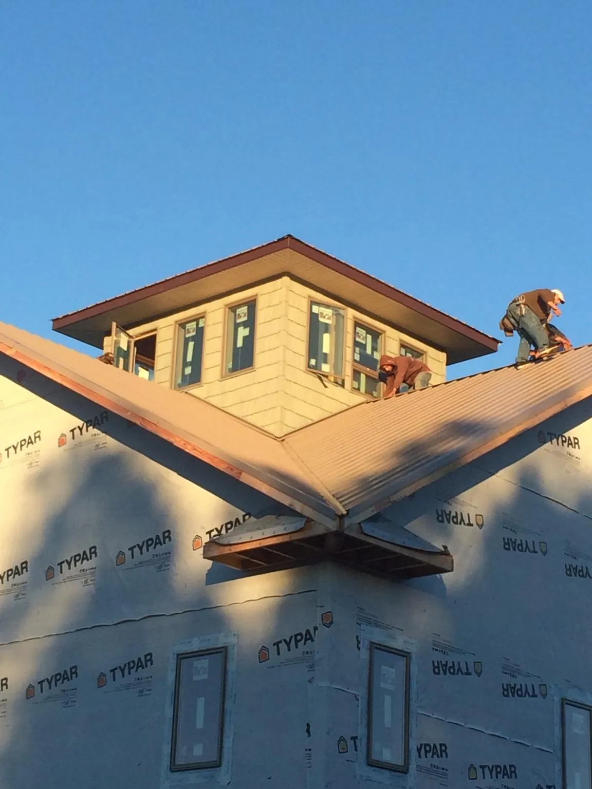 Roofers working around a rooftop cupola on a new metal roof at sunset — Roof Waterproofing in Talbott by Roofing Brothers